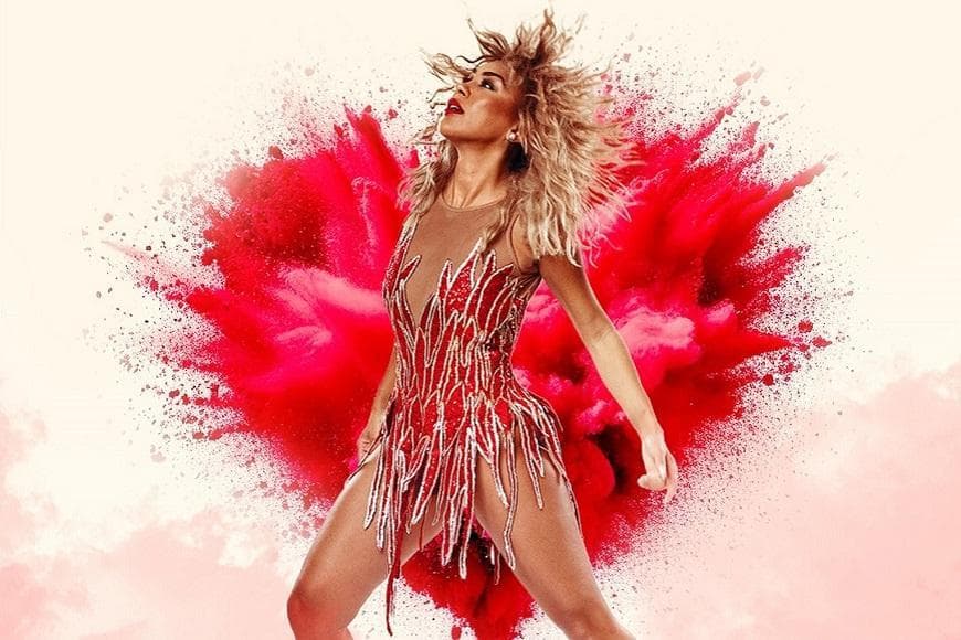 An image of the Tina Turner lookalike dressed a red diamanté outfit stood in front of a computer generated image of an exploding red heart