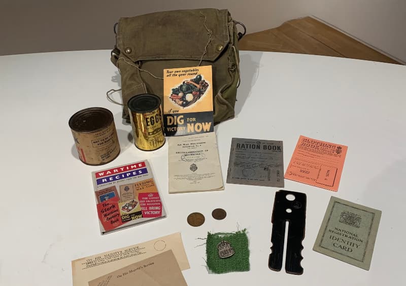 Contents of a handling box from the Museum of Edinburgh in relation to World War 2. Items include a duffle bag, a ration book, an air raid precautions leaflet, wartime recipes, clothing rations, national registration identity card, coins and a silver badge with the letters ARP.