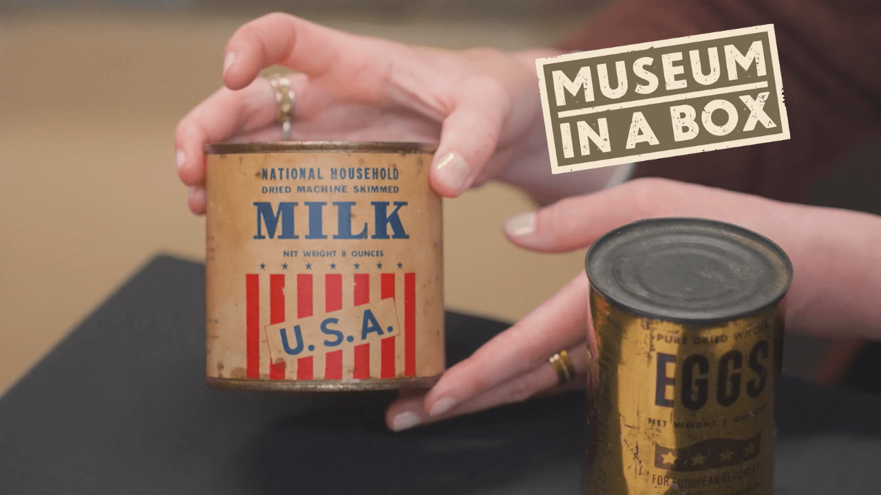 Hand examining an old tin of milk and tin of eggs from WW2