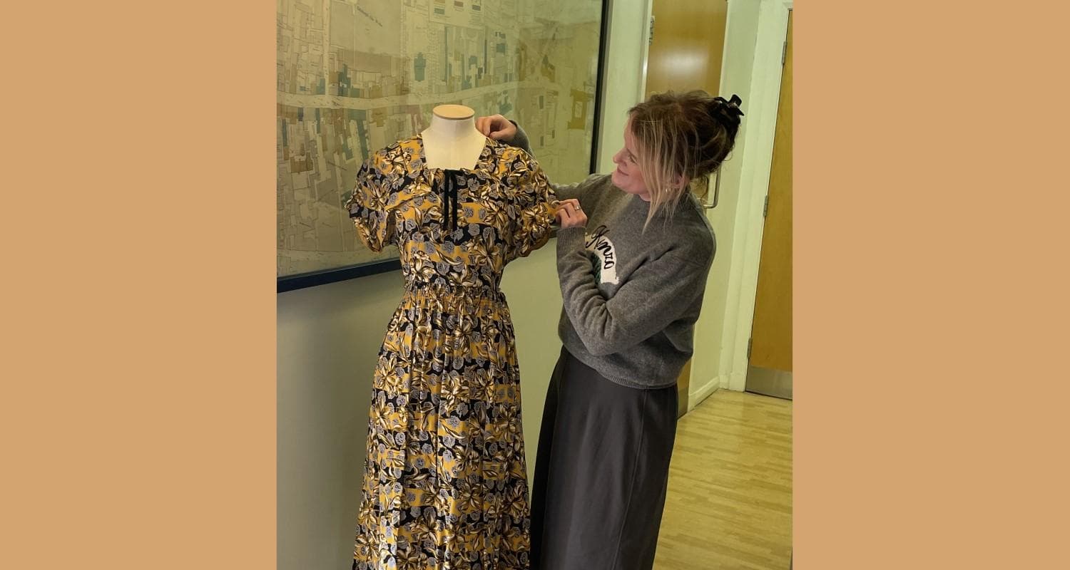 A curator inspects a colourful dress dating back to the World War 2 era