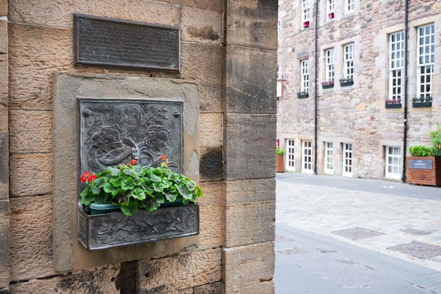 Small stone memorial to witches with a bed of orange flowers