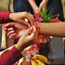 A Rakhi bracelet being put on someone's wrist