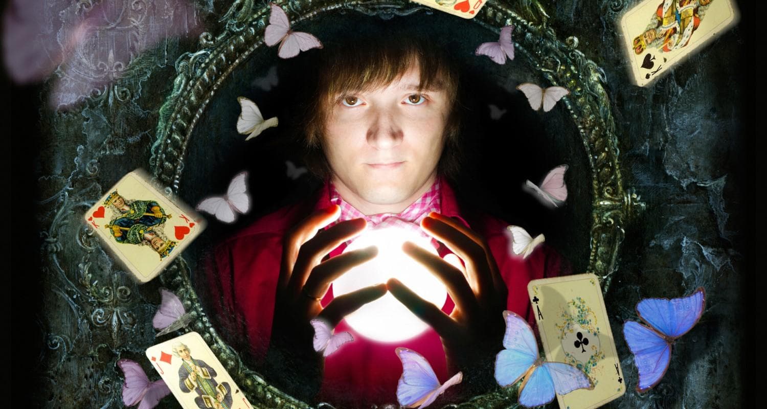 A magician holds a crystal ball, surrounded by colourful butterflies and playing cards. 