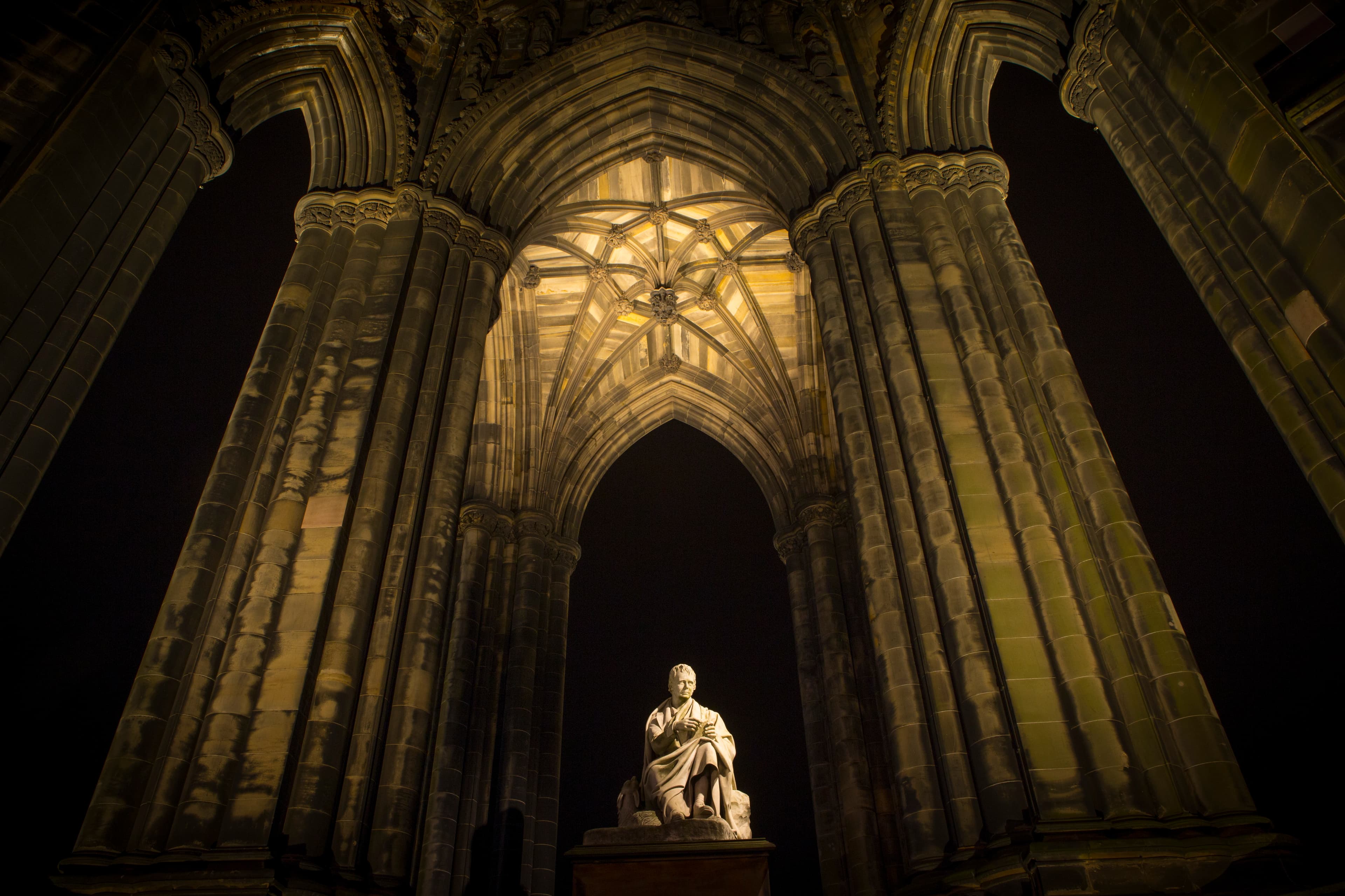 A statue sits prominently in the middle of a grand monument structure, showcasing intricate details against the architectural backdrop.