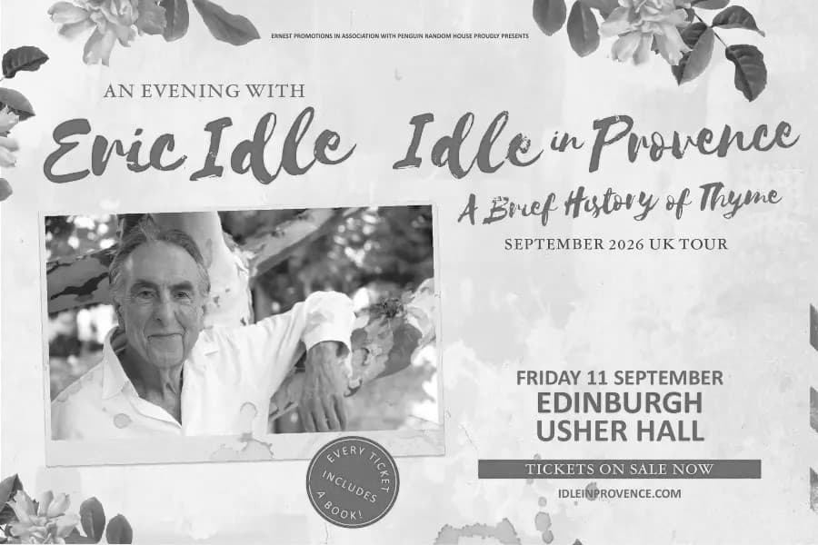 Image shows Eric Idle posing beside a tree