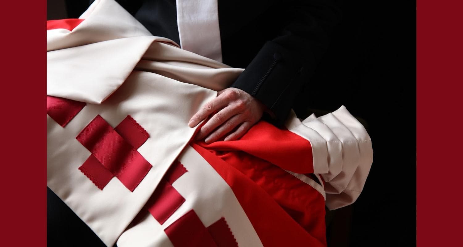 A photograph of a hand placed on red and white robes