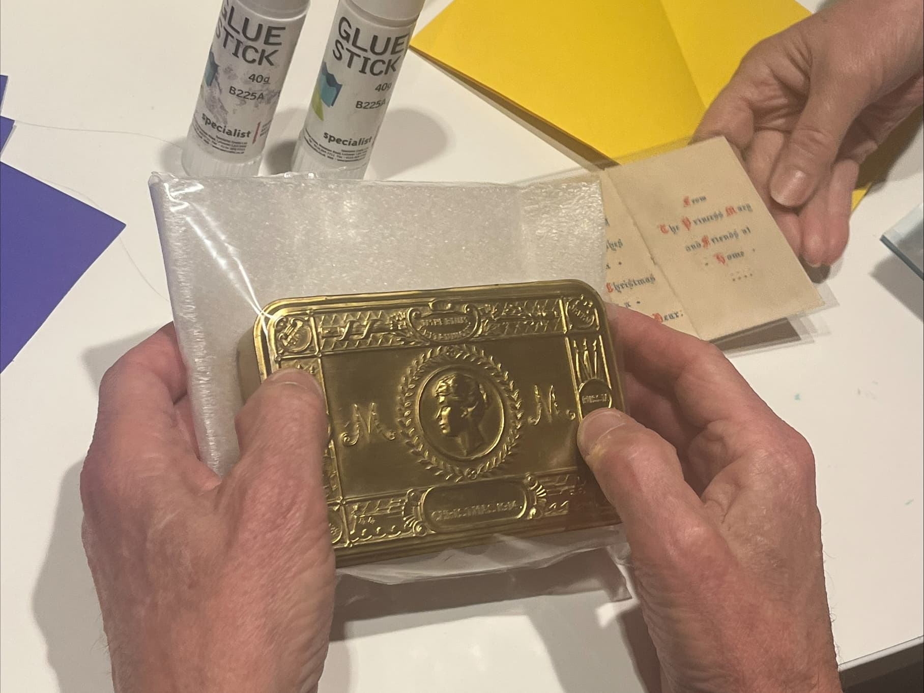 A person holds a shiny gold case above a table