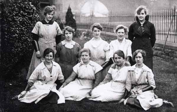 Black and White photo of working women seated in grounds of of a house