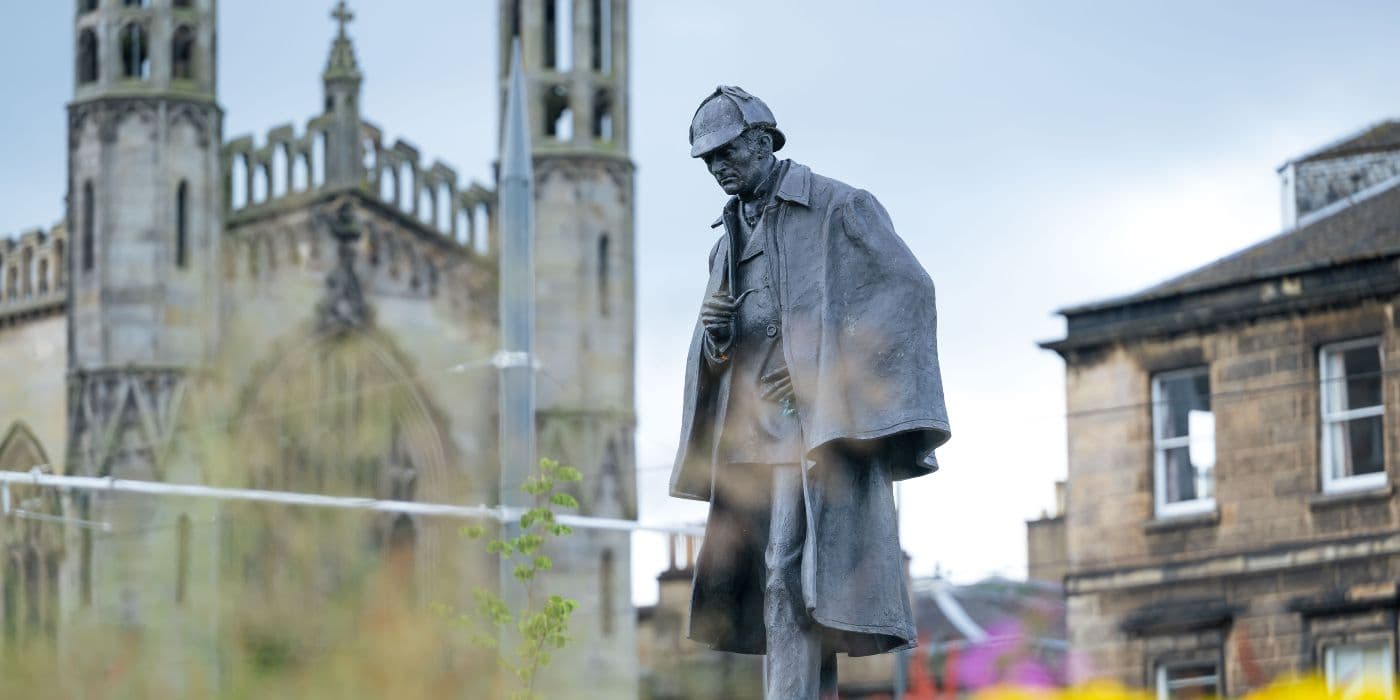 Statue of a man wearing a cap with a church in the background