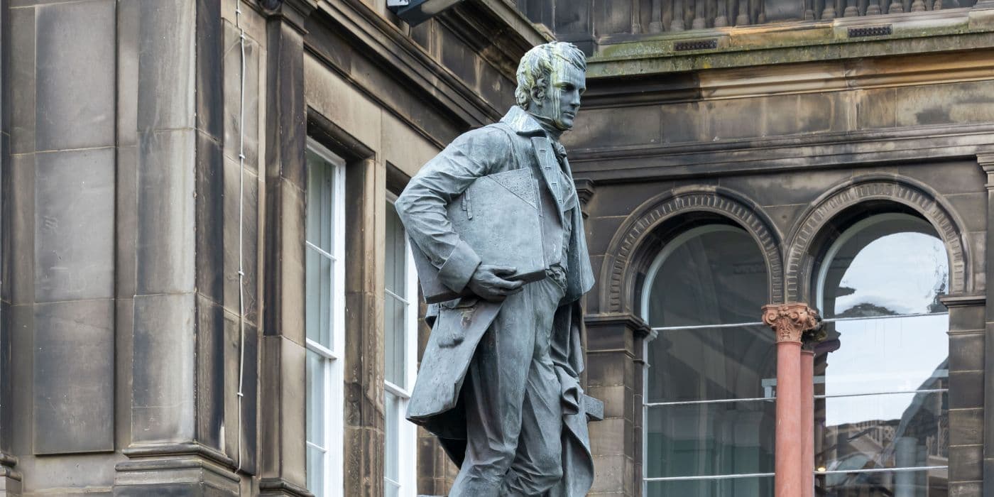 Statue of a man in front of a building with tall windows