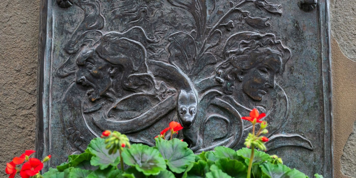 Engraved stone monument with a snake above a bed of orange flowers