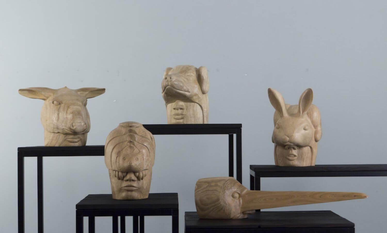 Five carved, wooden, animal masks , each one on a display table of varying heights.