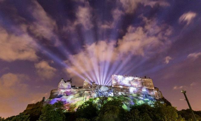 The Edinburgh Castle at night, illuminated with rays of colourful lights